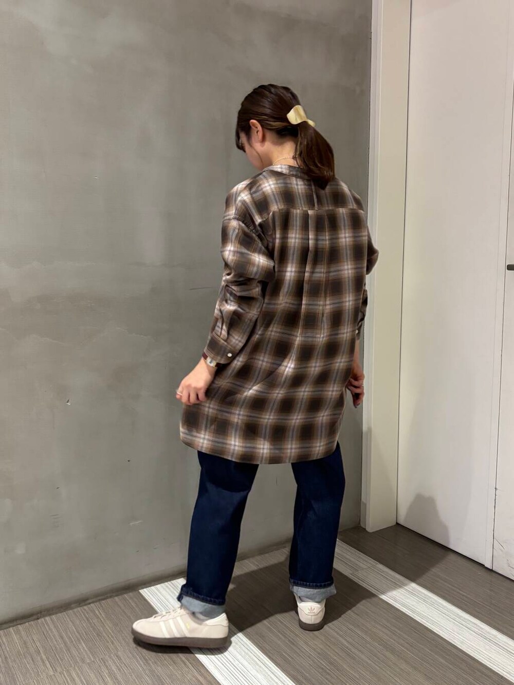 ブルー系のデニムパンツ、ブラウン系のシャツ/ブラウス、ホワイト系のスニーカーを着用したレディースの秋コーディネートの4枚目の写真