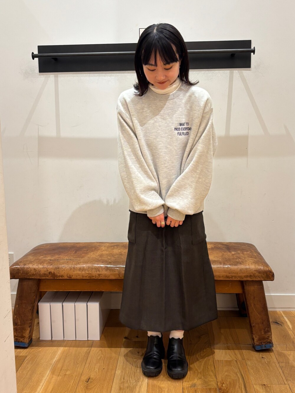 グレー系のニット/セーター、ホワイト系のTシャツ/カットソー、ブラウン系のスカートを着用したレディースの秋コーディネートの5枚目の写真