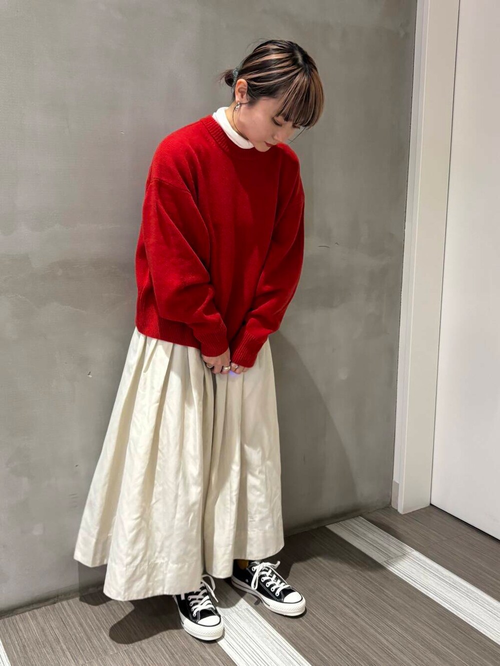 ブラック系のスニーカー、ホワイト系のスカート、レッド系のニット/セーターを着用したレディースの冬コーディネートの3枚目の写真
