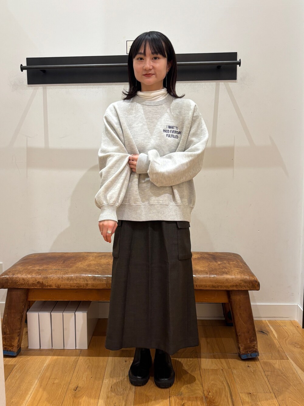 グレー系のニット/セーター、ホワイト系のTシャツ/カットソー、ブラウン系のスカートを着用したレディースの秋コーディネートの6枚目の写真