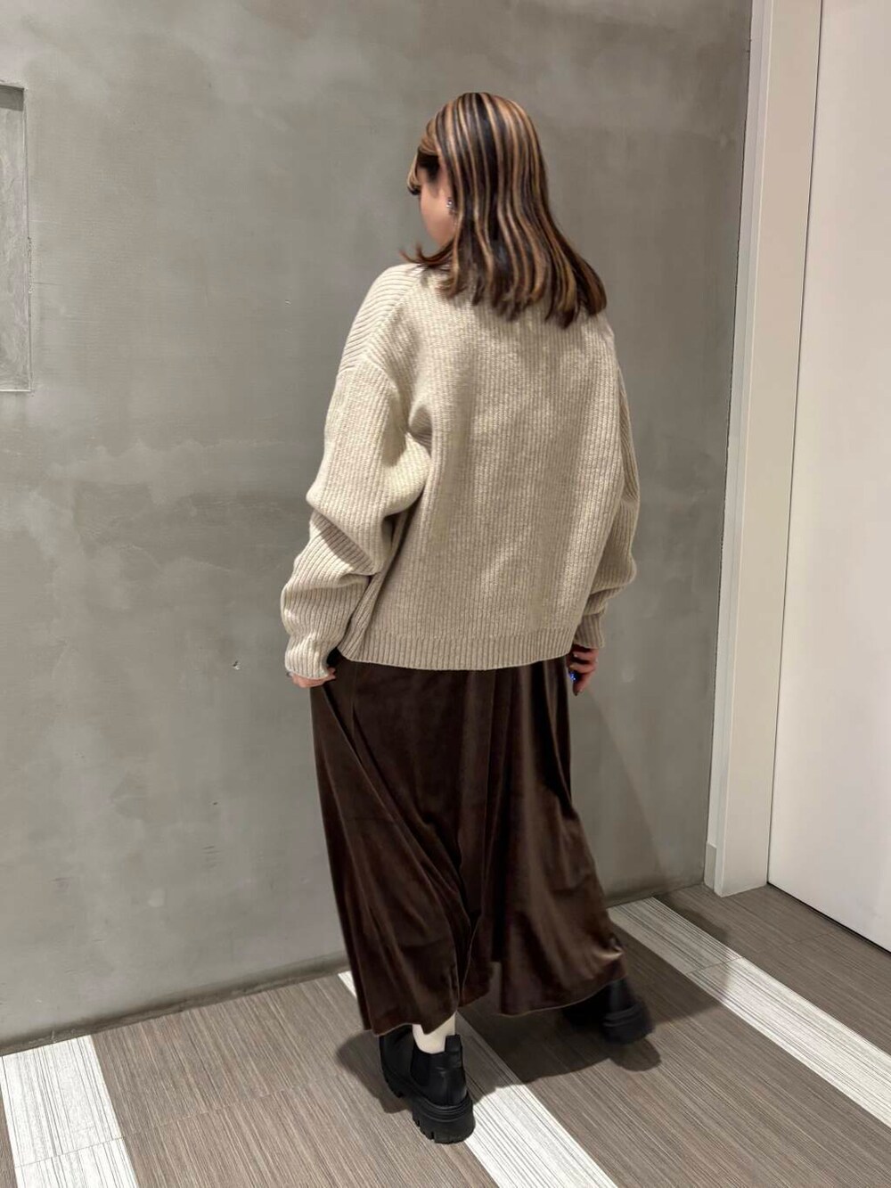 ベージュ系のカーディガン/ボレロ、ブラック系のブーツ、グリーン系のワンピースを着用したレディースの冬コーディネートの2枚目の写真