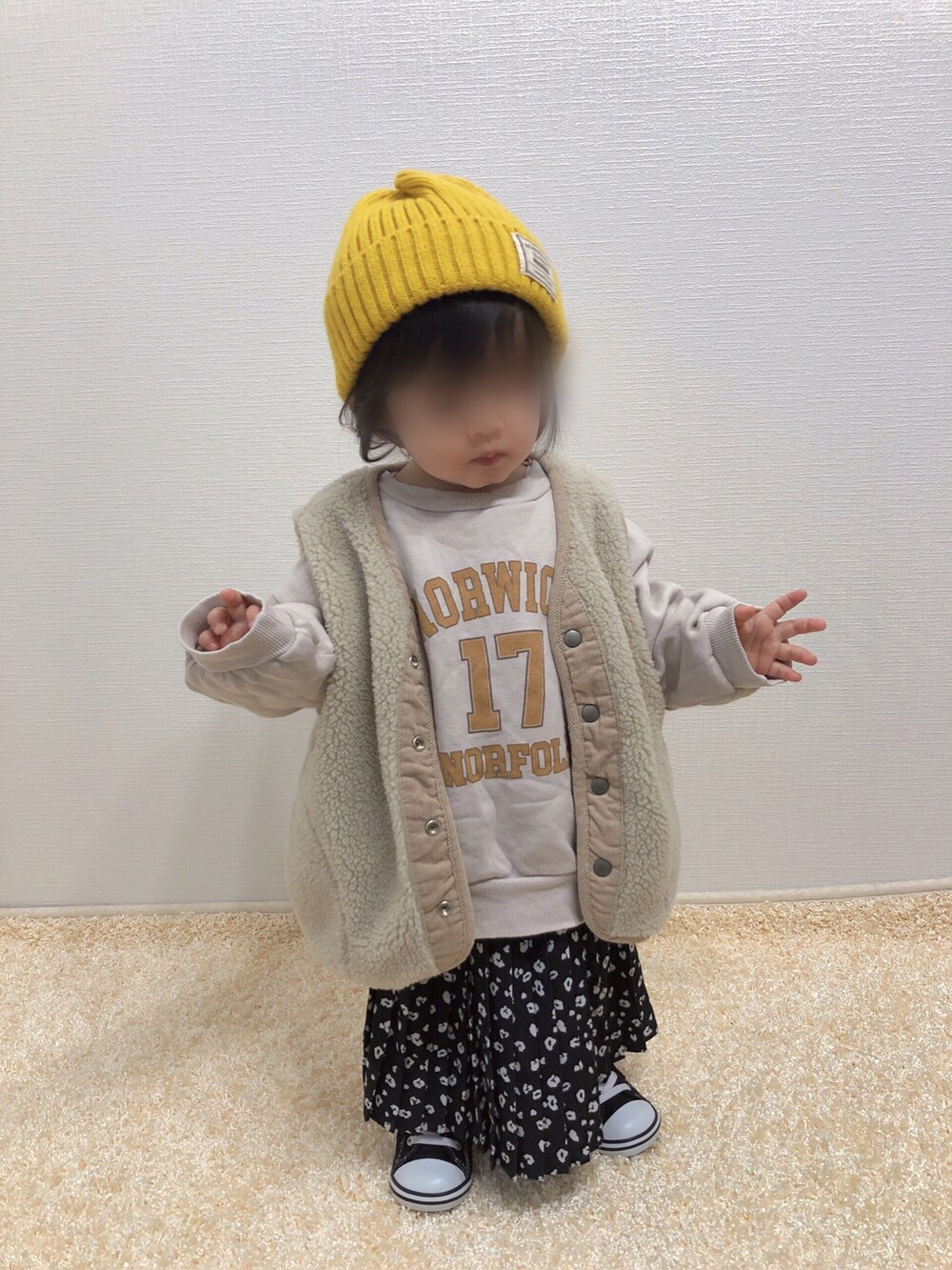 ベージュ系のスウェット、ベージュ系のベスト、ブラック系のスカートを着用したキッズの冬コーディネートの2枚目の写真