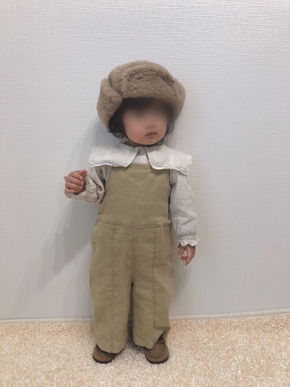 ホワイト系のシャツ/ブラウス、ベージュ系のサロペット/オーバーオール、ベージュ系のモカシン/デッキシューズを着用したキッズの冬コーディネートの2枚目の写真