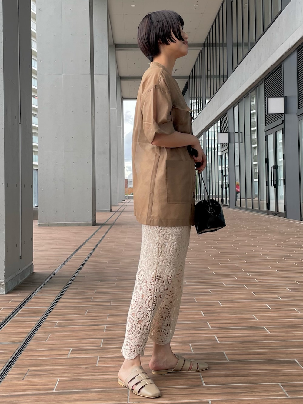 ブラック系のショルダーバッグ、ホワイト系のスカート、ベージュ系のサンダルを着用したレディースの夏コーディネートの2枚目の写真