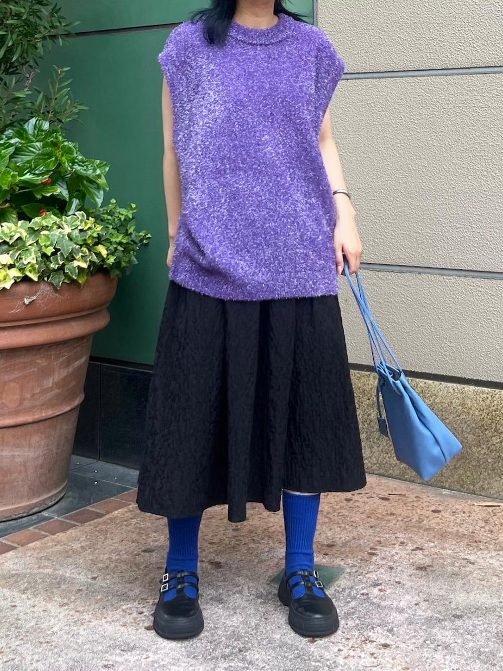 ブラック系のスカート、ブラック系のスニーカー、ブルー系のショルダーバッグを着用したレディースの夏コーディネートの2枚目の写真