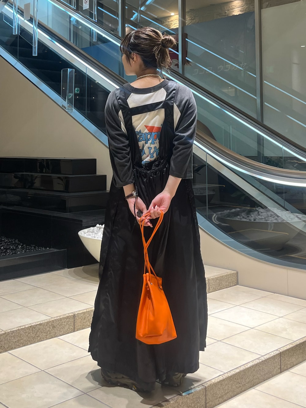 グレー系のスニーカー、オレンジ系のショルダーバッグ、ブラック系のワンピース/ドレスを着用したレディースの夏コーディネートの3枚目の写真