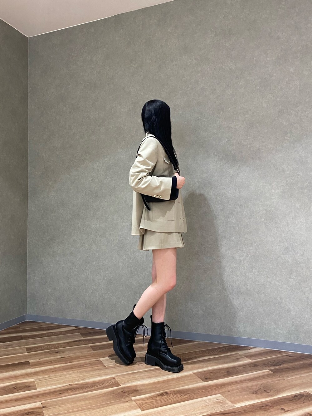 ベージュ系のテーラードジャケット、ブラック系のブーツ、ベージュ系のスカートを着用したレディースの冬コーディネートの2枚目の写真