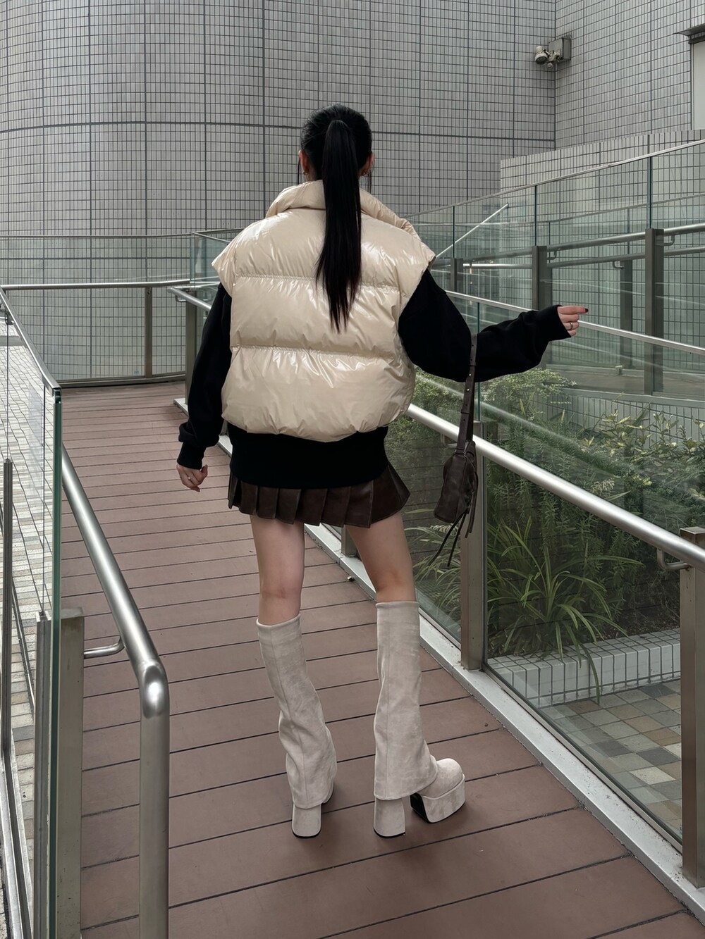 レッド系のショルダーバッグ、ホワイト系のダウンベスト、グレー系のスカートを着用したレディースの秋コーディネートの3枚目の写真