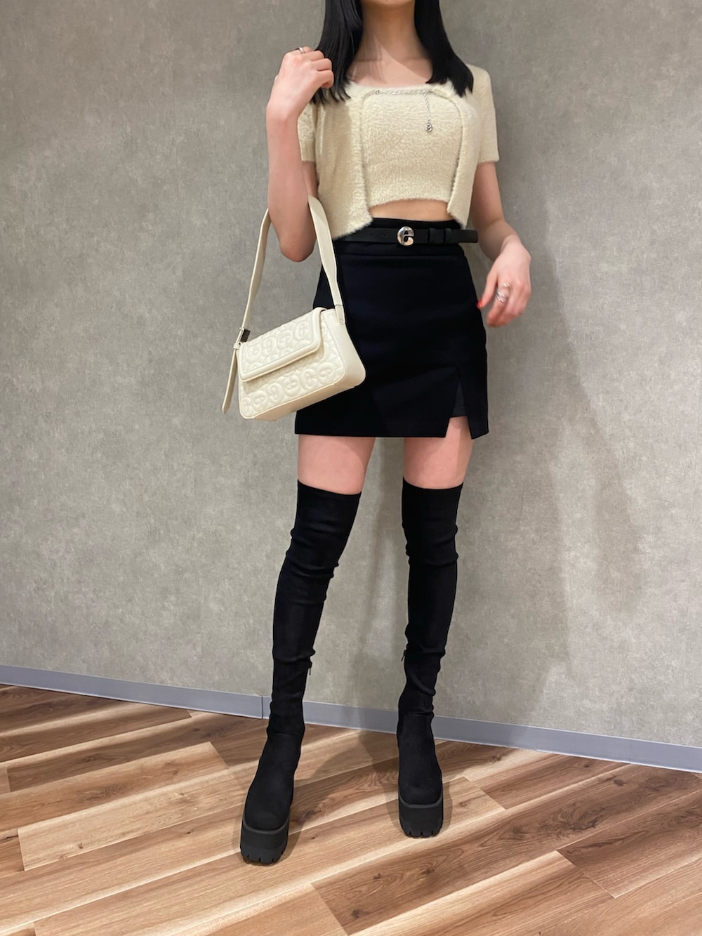 ブラック系のスカート、ホワイト系のハンドバッグ、ブラック系のブーツを着用したレディースの夏コーディネートの4枚目の写真