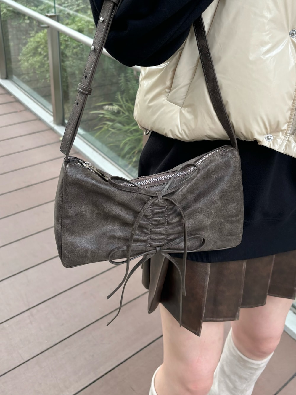 レッド系のショルダーバッグ、ホワイト系のダウンベスト、グレー系のスカートを着用したレディースの秋コーディネートの6枚目の写真