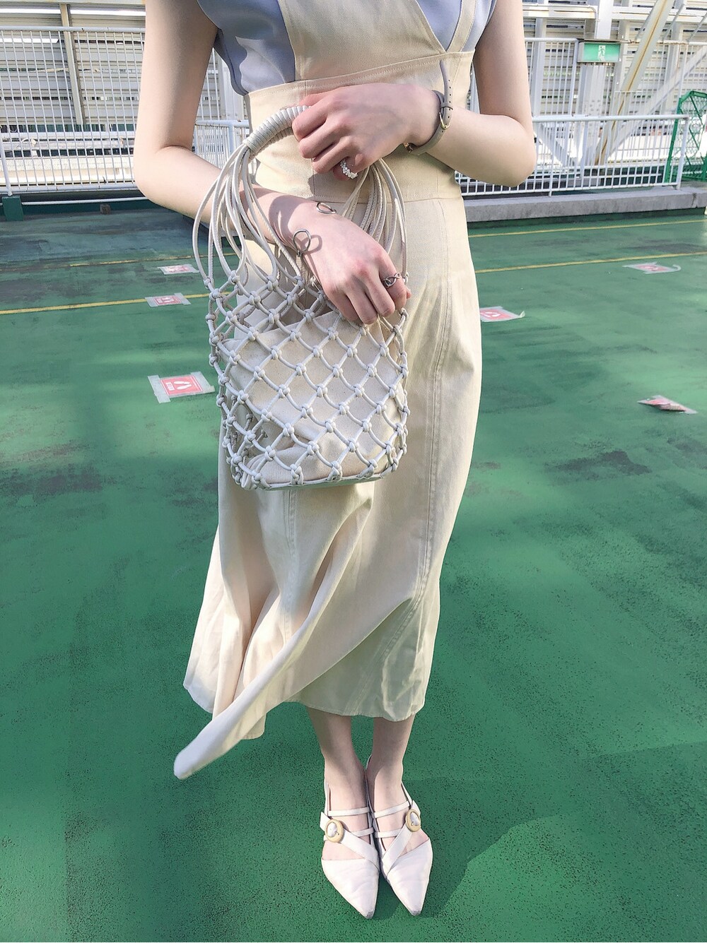 ホワイト系のハンドバッグ、ホワイト系のワンピース、ホワイト系のパンプスを着用したレディースの春コーディネートの4枚目の写真