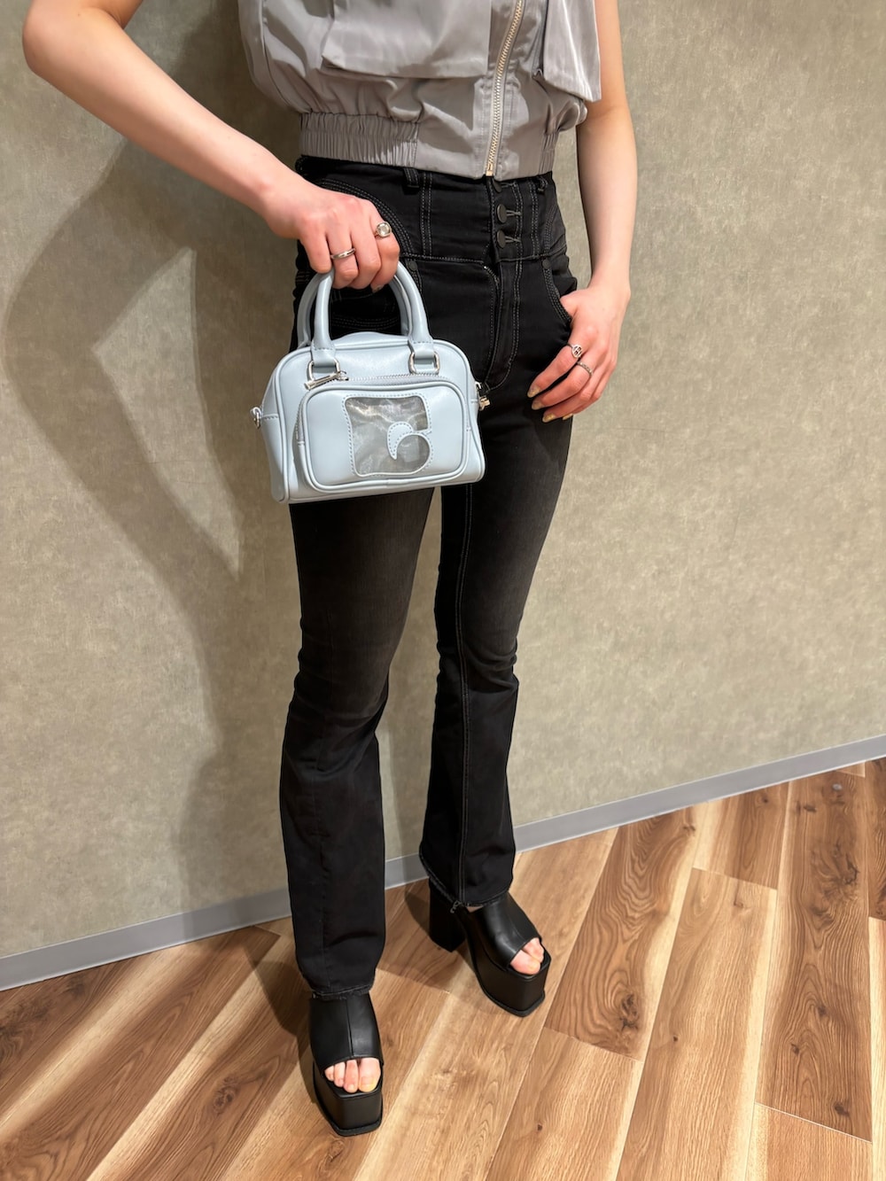 ブラック系のハンドバッグ、ブラック系のデニムパンツ、ブラック系のサンダルを着用したレディースの春コーディネートの5枚目の写真