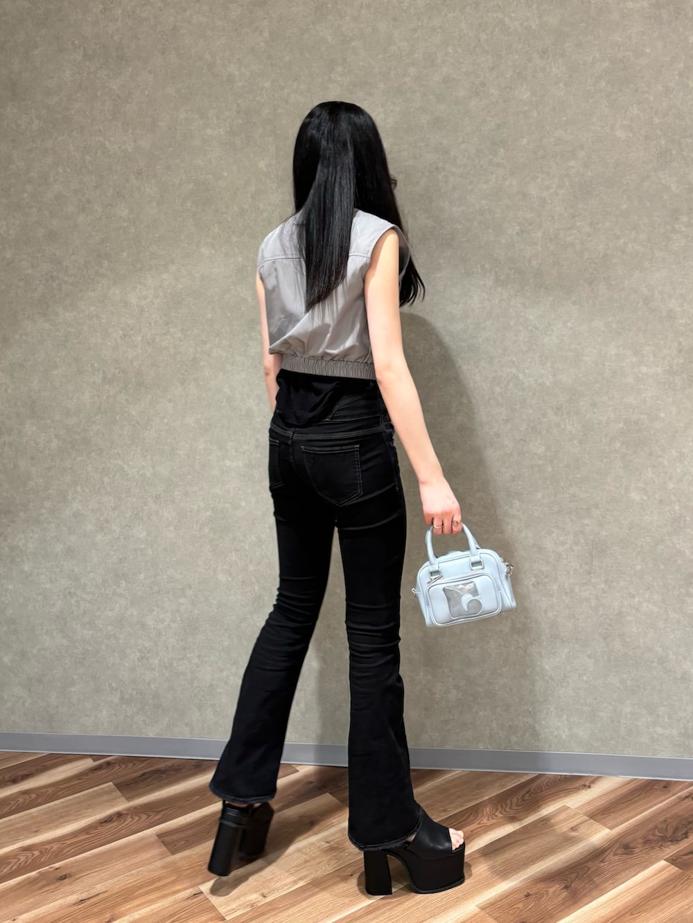 ブラック系のハンドバッグ、ブラック系のデニムパンツ、ブラック系のサンダルを着用したレディースの春コーディネートの3枚目の写真
