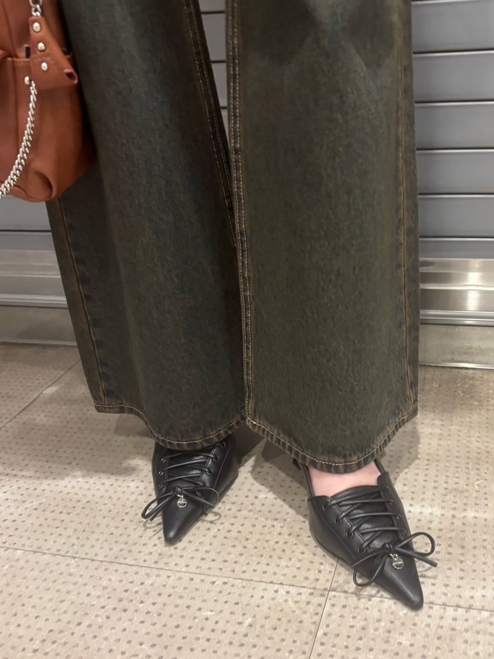 ブルー系のデニムパンツ、ブラウン系のハンドバッグ、ブルー系のタンクトップを着用したレディースの春コーディネートの6枚目の写真