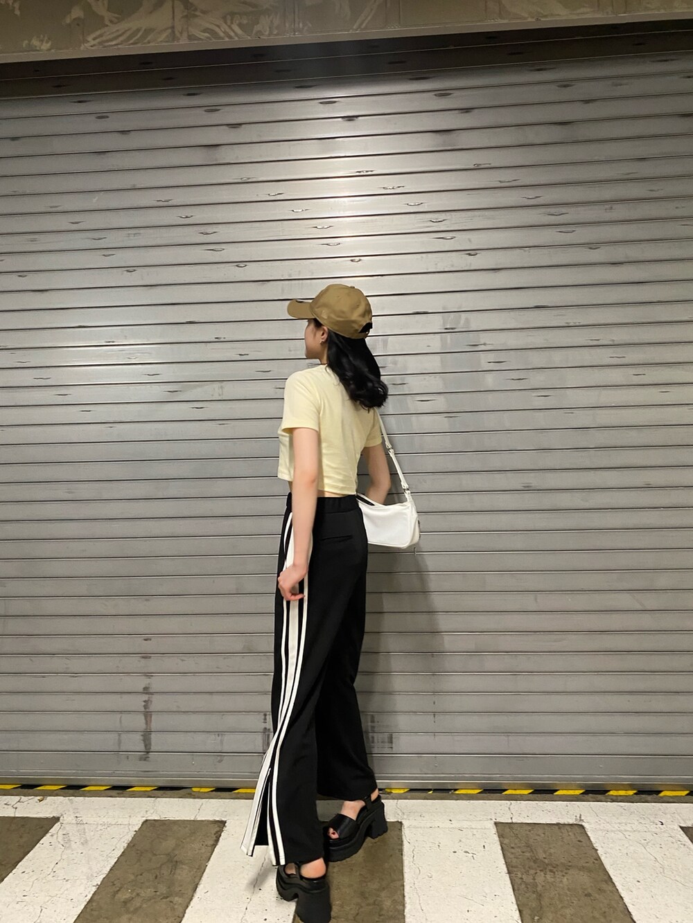 オレンジ系のTシャツ/カットソー、ブラック系のその他パンツ、ホワイト系のハンドバッグを着用したレディースの夏コーディネートの3枚目の写真