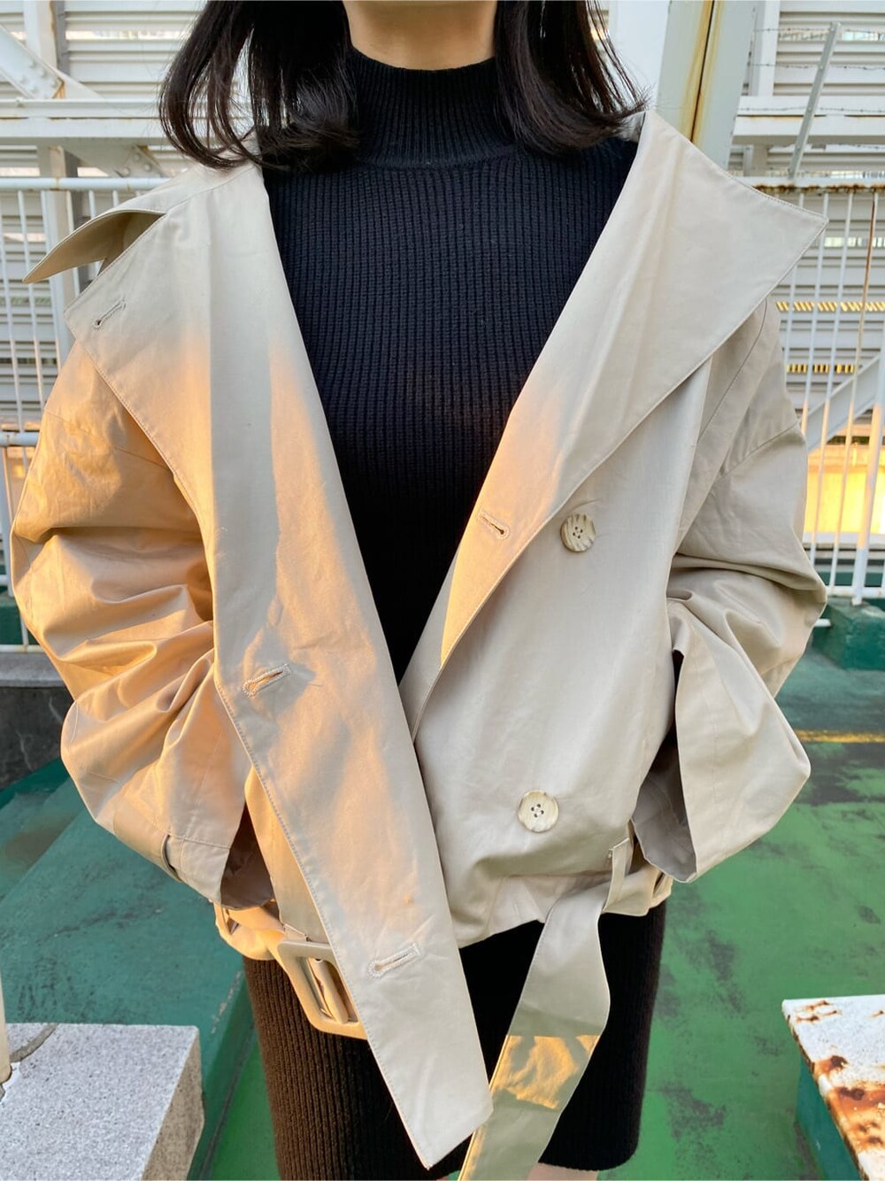 ブラック系のワンピース、ベージュ系のトレンチコート、ブラック系のブーツを着用したレディースの冬コーディネートの5枚目の写真