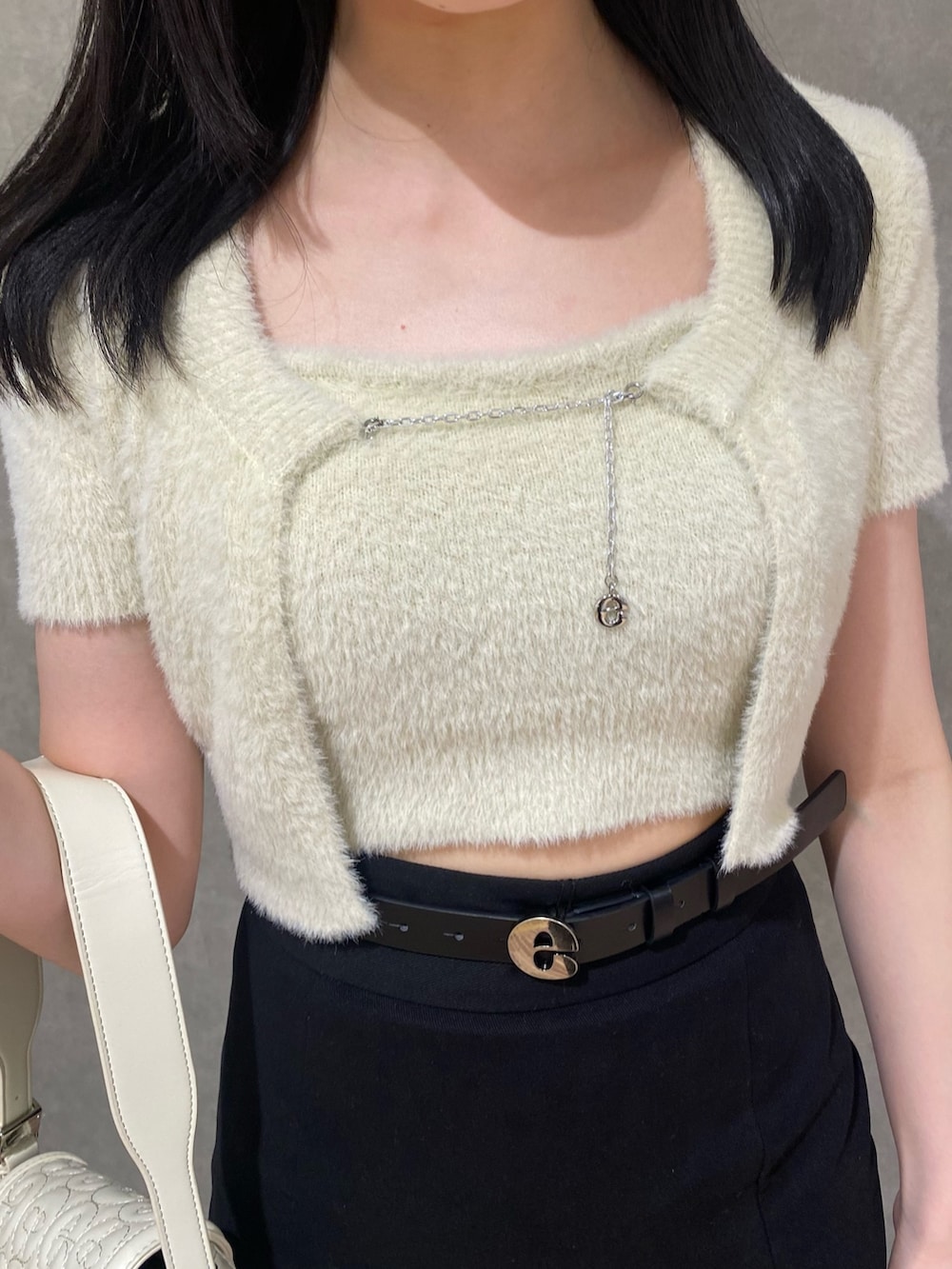 ブラック系のスカート、ホワイト系のハンドバッグ、ブラック系のブーツを着用したレディースの夏コーディネートの5枚目の写真