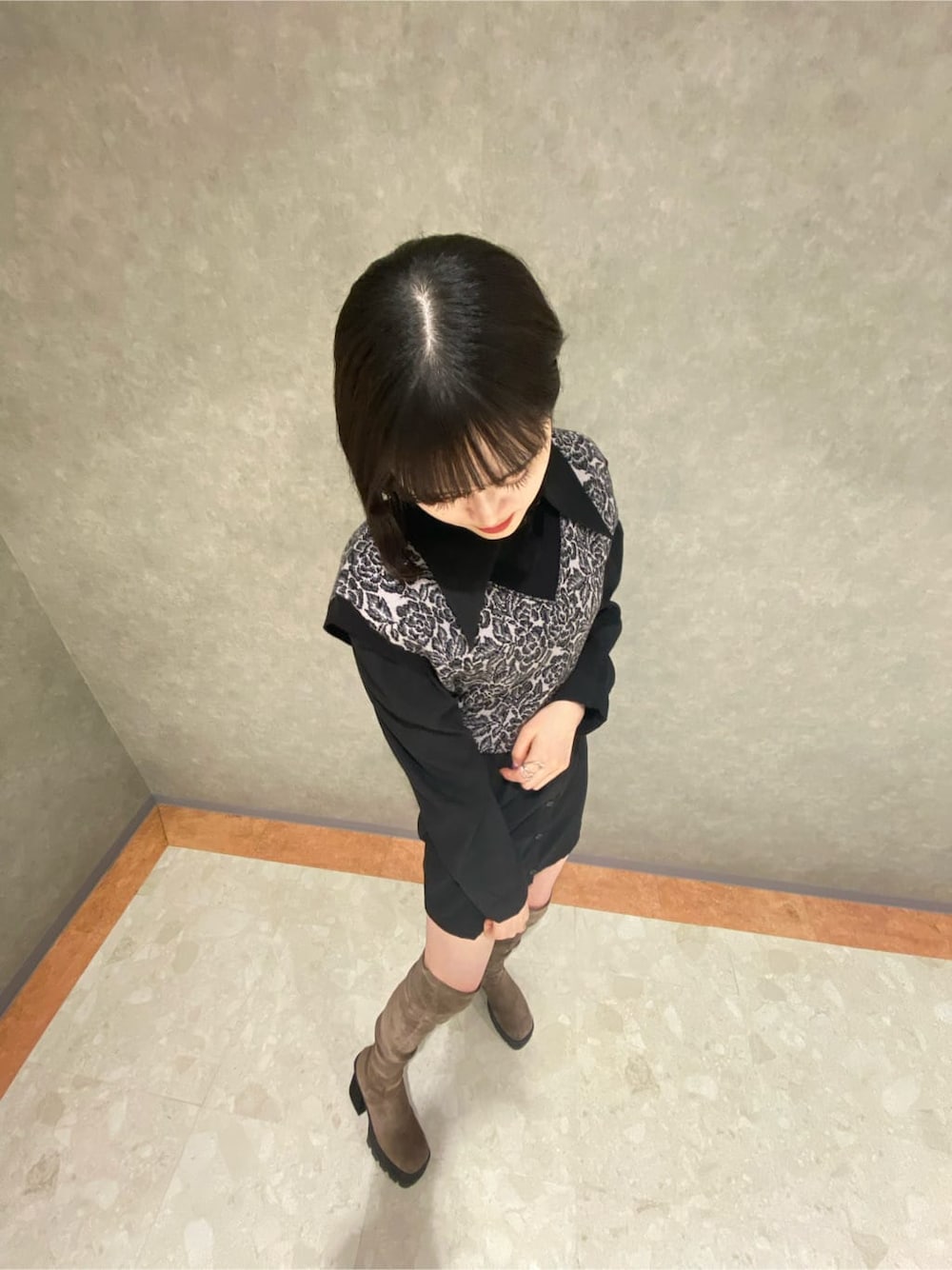 ブラック系のワンピース、ベージュ系のブーツ、その他のベストを着用したレディースの秋コーディネートの3枚目の写真