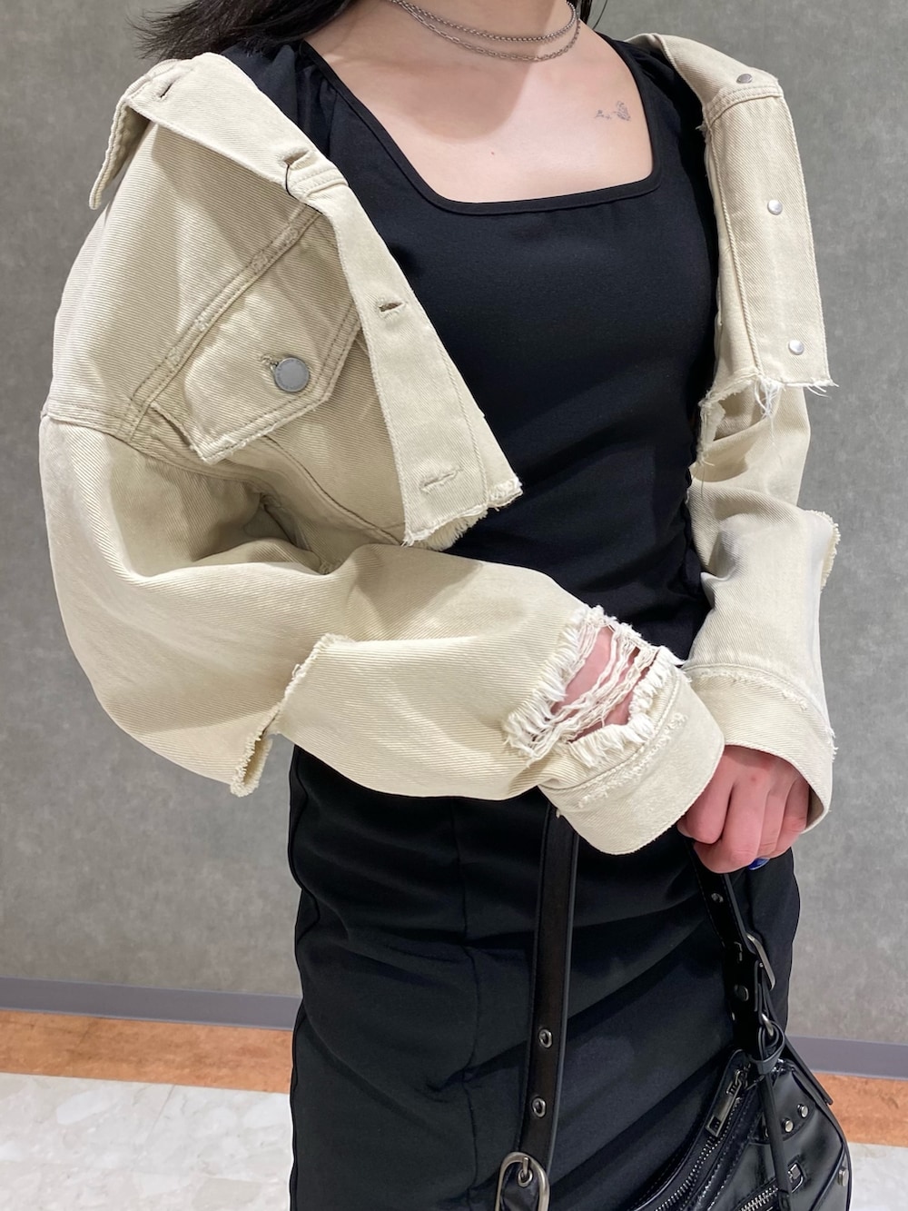 ホワイト系のデニムジャケット、ブラック系のハンドバッグ、ブラック系のサンダルを着用したレディースの春コーディネートの5枚目の写真