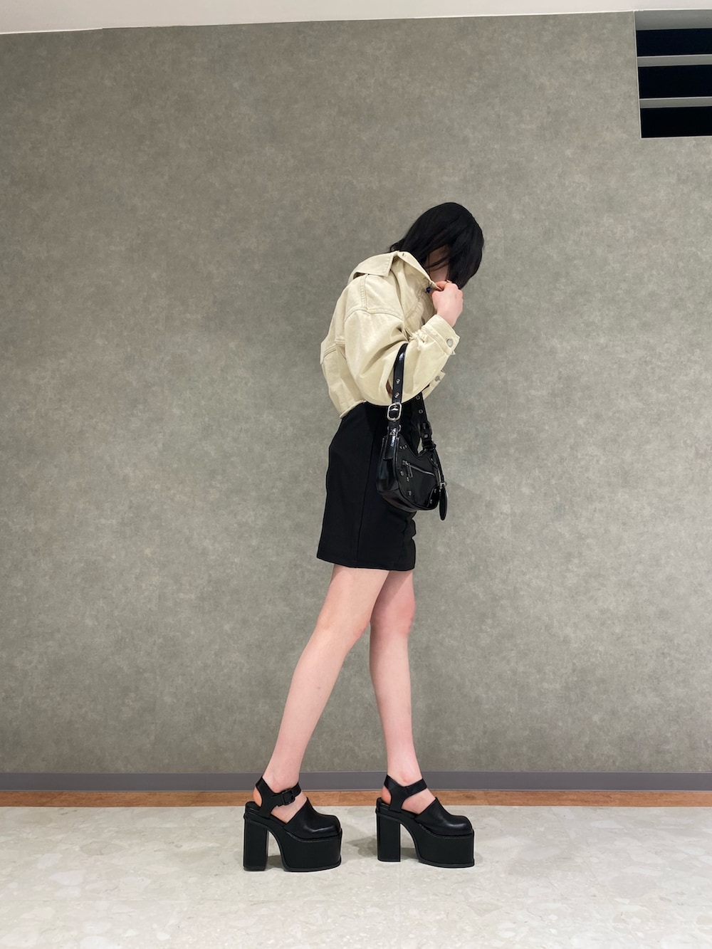 ホワイト系のデニムジャケット、ブラック系のハンドバッグ、ブラック系のサンダルを着用したレディースの春コーディネートの2枚目の写真