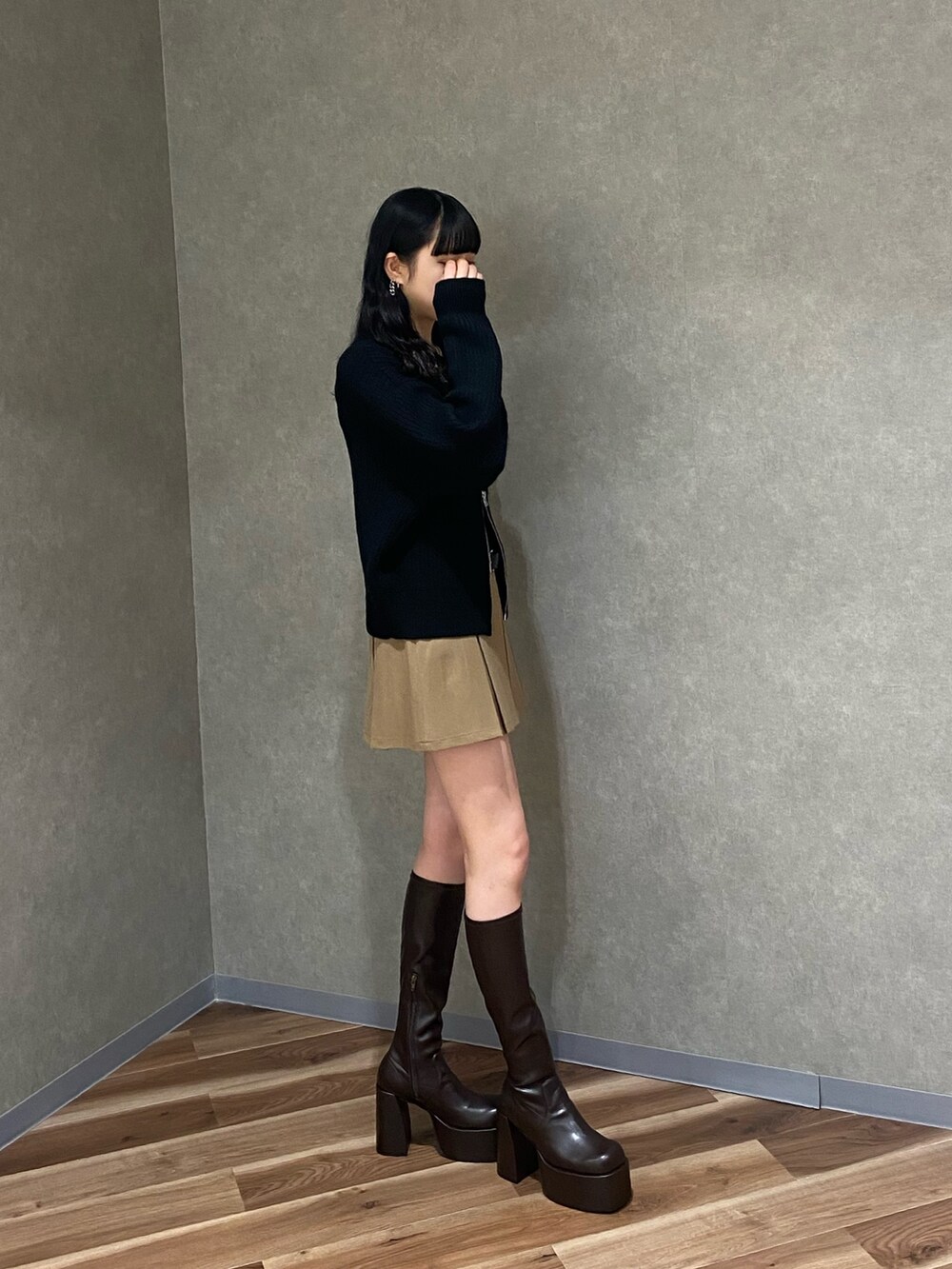 ブラウン系のブーツ、ベージュ系のスカート、ブラック系のニット/セーターを着用したレディースの冬コーディネートの2枚目の写真