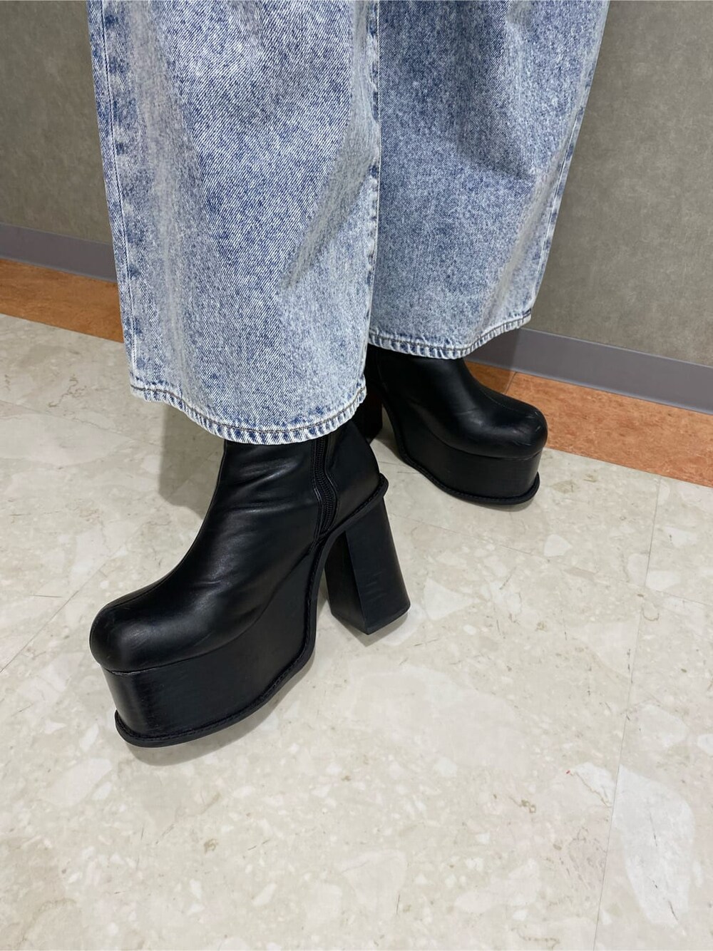 ブラック系のブーツ、ブラック系のハンドバッグ、ブルー系のデニムパンツを着用したレディースの秋コーディネートの5枚目の写真