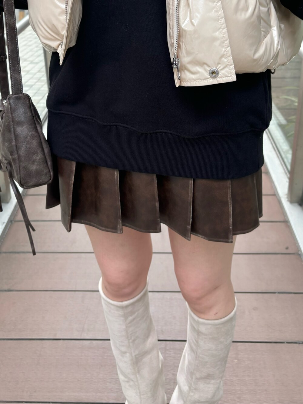 レッド系のショルダーバッグ、ホワイト系のダウンベスト、グレー系のスカートを着用したレディースの秋コーディネートの5枚目の写真