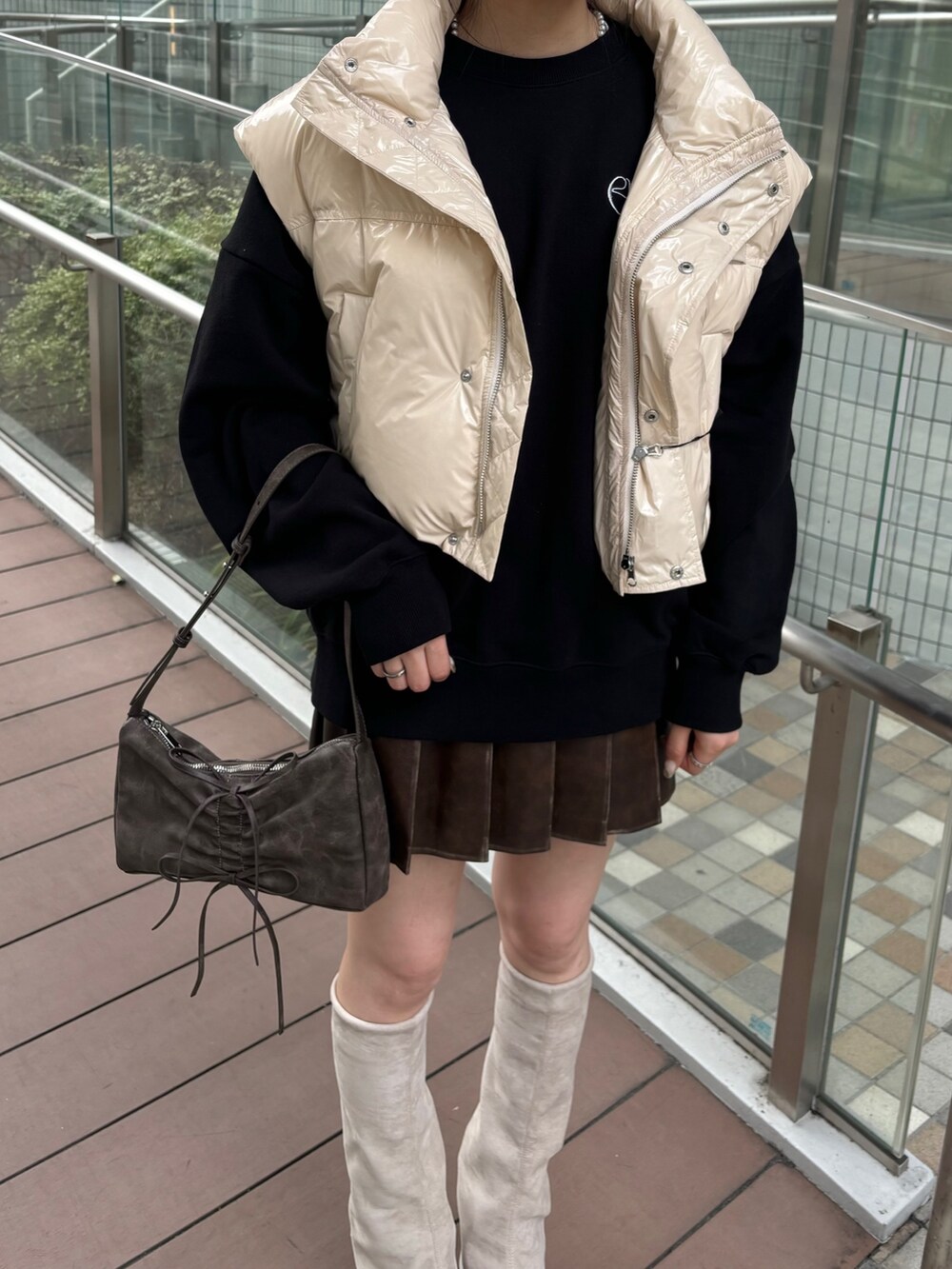 レッド系のショルダーバッグ、ホワイト系のダウンベスト、グレー系のスカートを着用したレディースの秋コーディネートの4枚目の写真