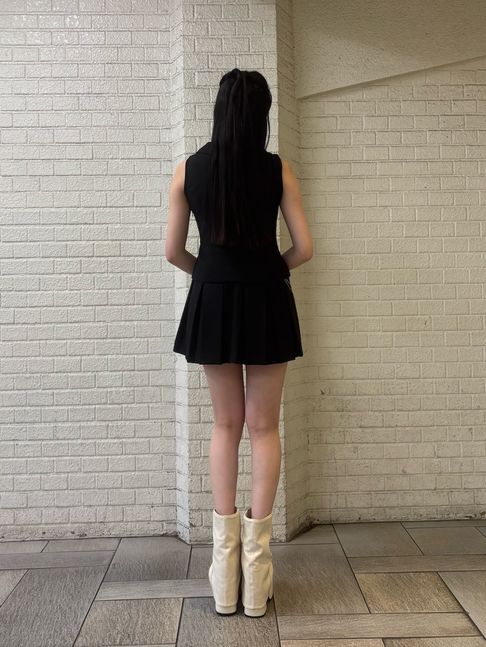 ブラック系のニット/セーター、ホワイト系のサンダル、ブラック系のワンピースを着用したレディースの春コーディネートの3枚目の写真