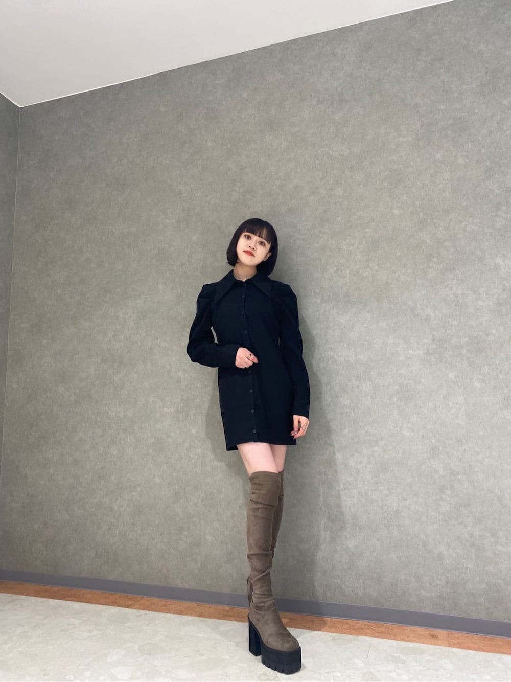 ブラック系のワンピース、ベージュ系のブーツ、その他のベストを着用したレディースの秋コーディネートの2枚目の写真