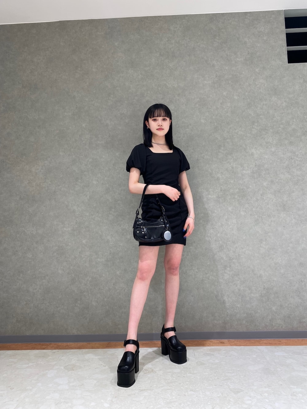 ホワイト系のデニムジャケット、ブラック系のハンドバッグ、ブラック系のサンダルを着用したレディースの春コーディネートの3枚目の写真