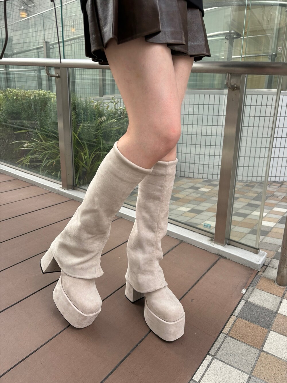 レッド系のショルダーバッグ、ホワイト系のダウンベスト、グレー系のスカートを着用したレディースの秋コーディネートの7枚目の写真