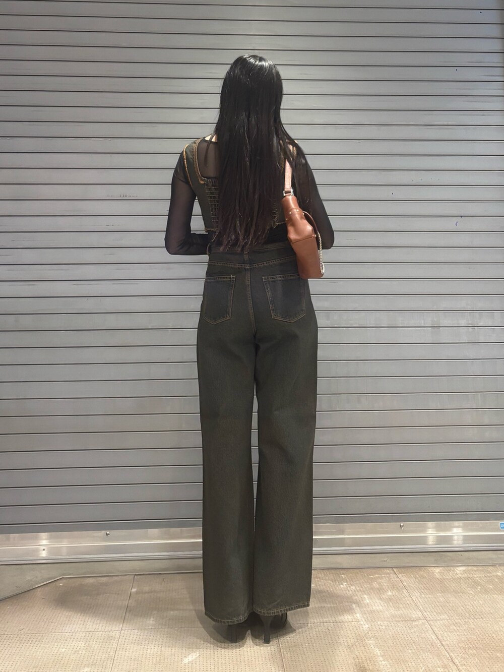 ブルー系のデニムパンツ、ブラウン系のハンドバッグ、ブルー系のタンクトップを着用したレディースの春コーディネートの3枚目の写真