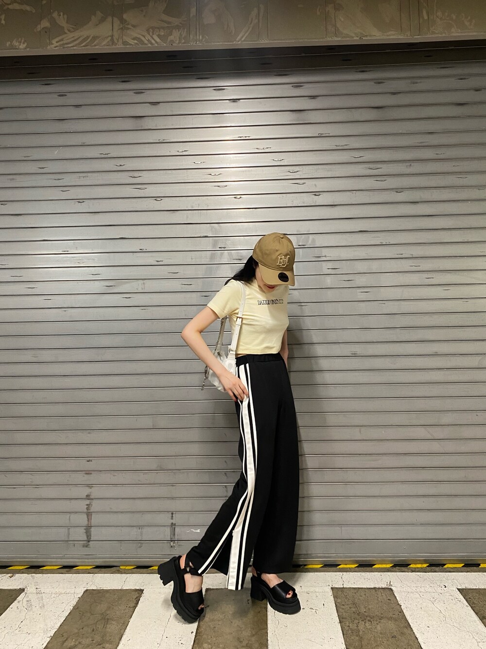 オレンジ系のTシャツ/カットソー、ブラック系のその他パンツ、ホワイト系のハンドバッグを着用したレディースの夏コーディネートの2枚目の写真