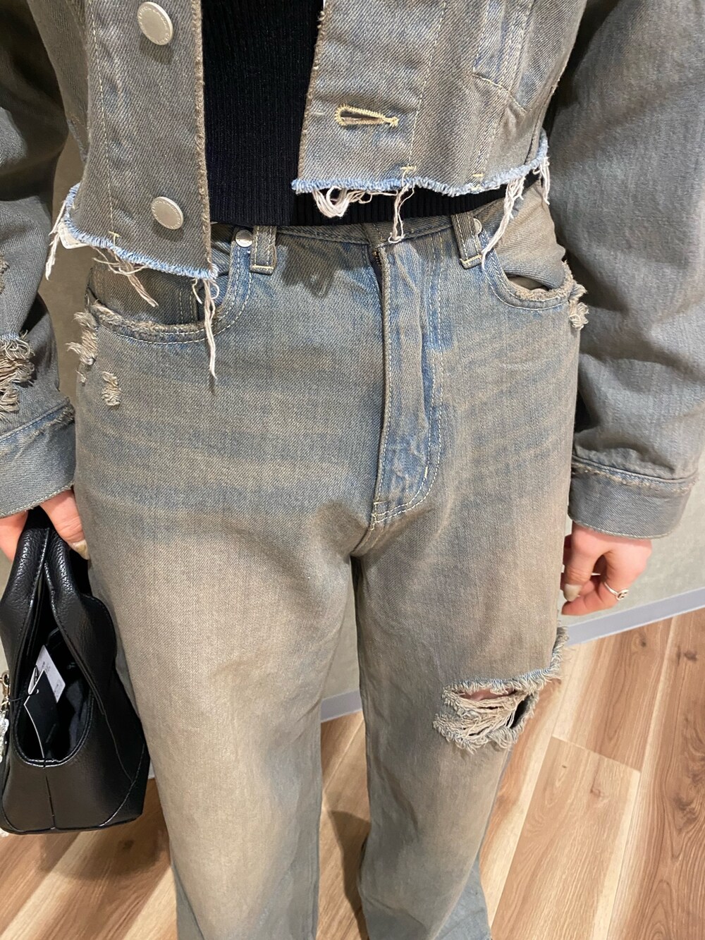 グレー系のデニムパンツ、ブラック系のスニーカー、ブラック系のハンドバッグを着用したレディースの冬コーディネートの6枚目の写真