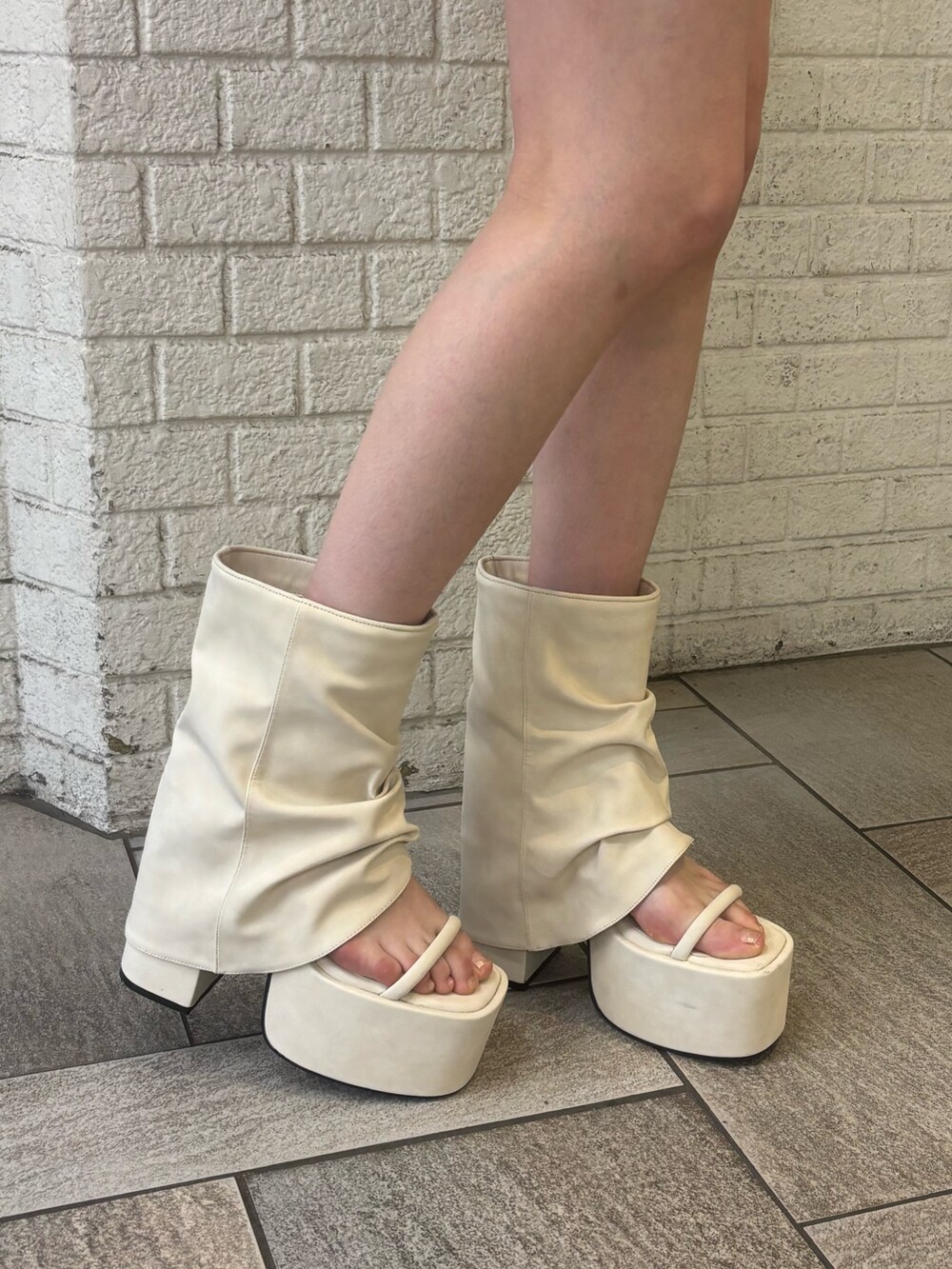 ブラック系のニット/セーター、ホワイト系のサンダル、ブラック系のワンピースを着用したレディースの春コーディネートの5枚目の写真