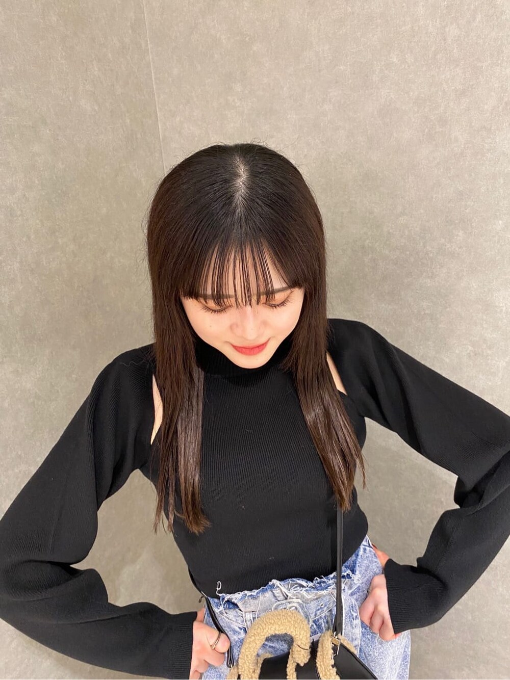 ブラック系のブーツ、ブラック系のハンドバッグ、ブルー系のデニムパンツを着用したレディースの秋コーディネートの3枚目の写真