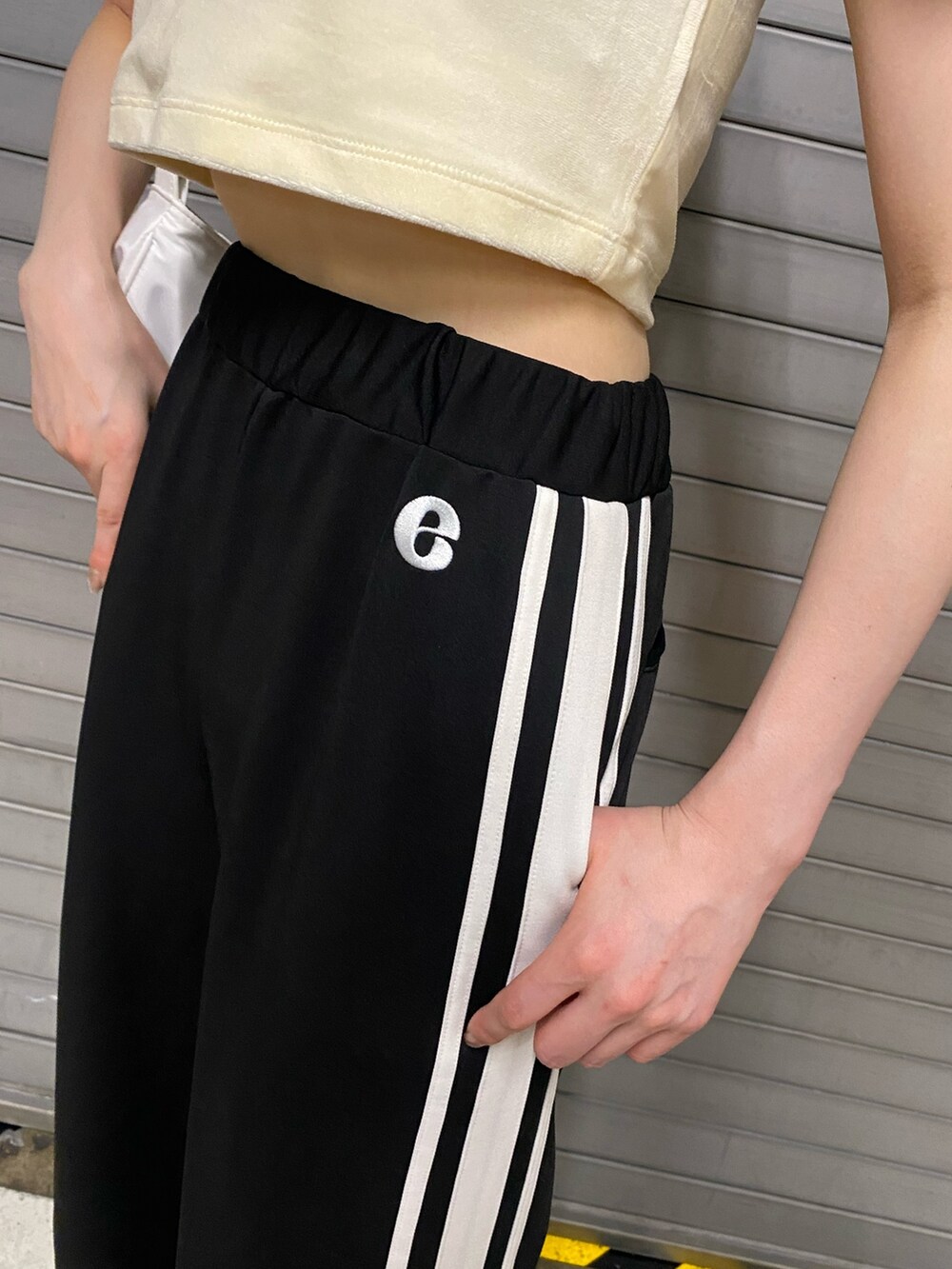 オレンジ系のTシャツ/カットソー、ブラック系のその他パンツ、ホワイト系のハンドバッグを着用したレディースの夏コーディネートの6枚目の写真