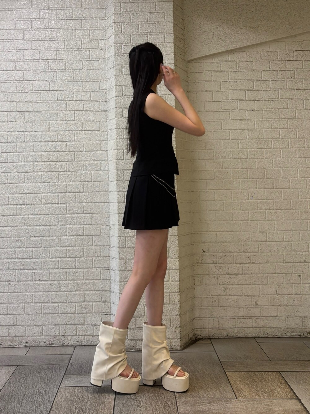 ブラック系のニット/セーター、ホワイト系のサンダル、ブラック系のワンピースを着用したレディースの春コーディネートの2枚目の写真