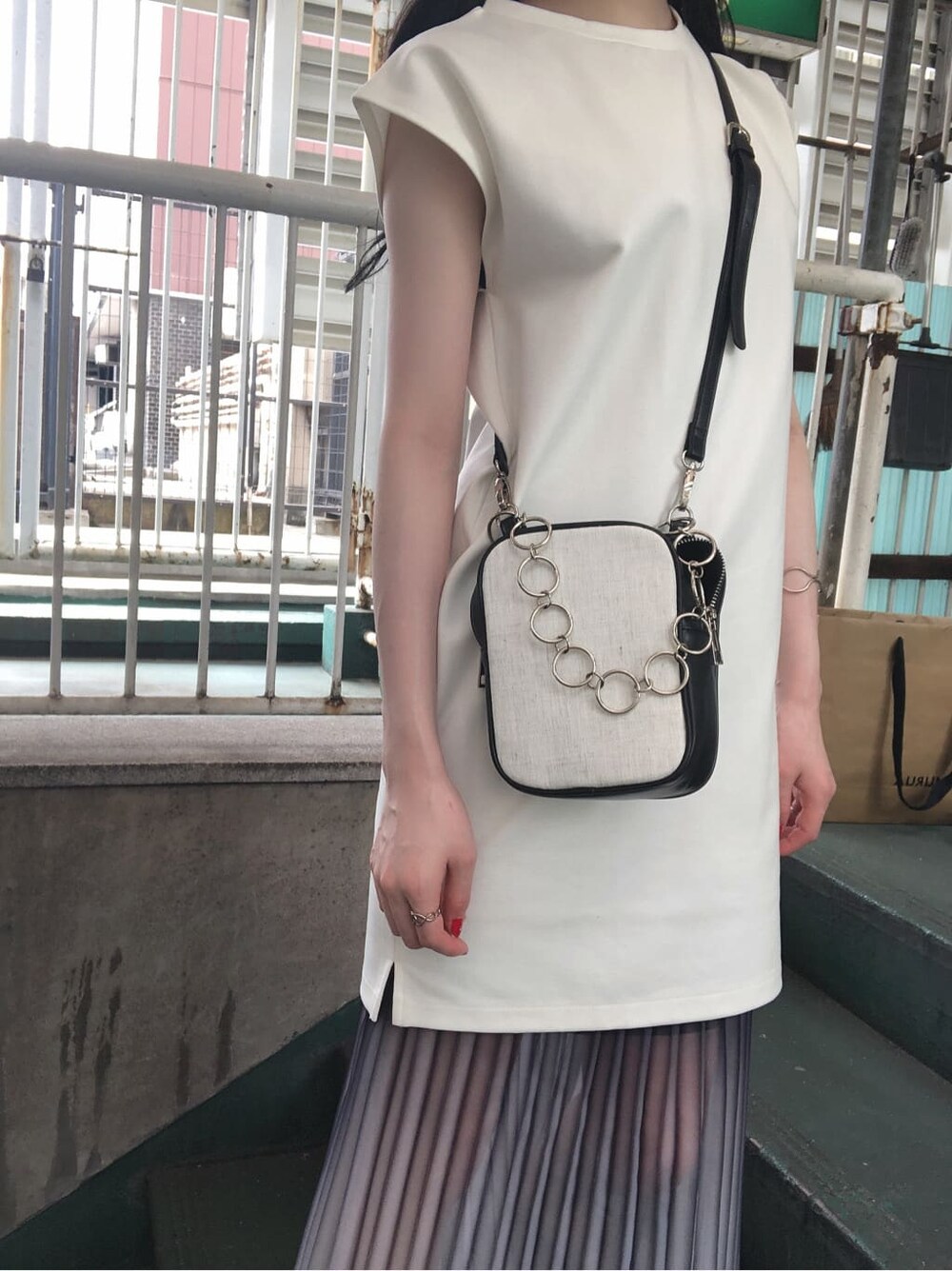 ホワイト系のワンピース、ブルー系のスカート、ブラック系のハンドバッグを着用したレディースの夏コーディネートの3枚目の写真