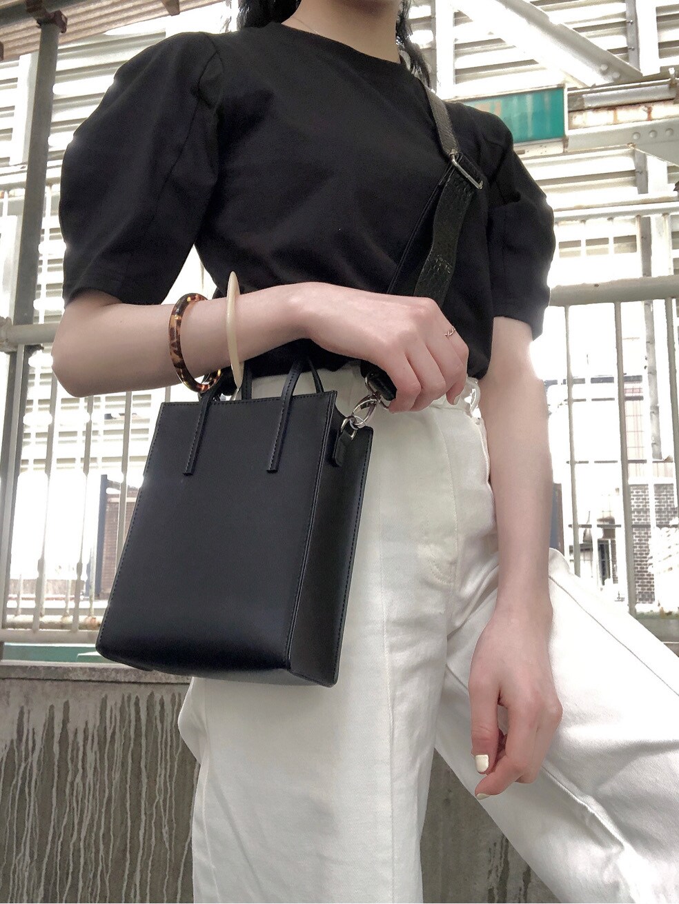 ホワイト系のその他パンツ、ブラック系のTシャツ/カットソー、ブラック系のショルダーバッグを着用したレディースの春コーディネートの5枚目の写真