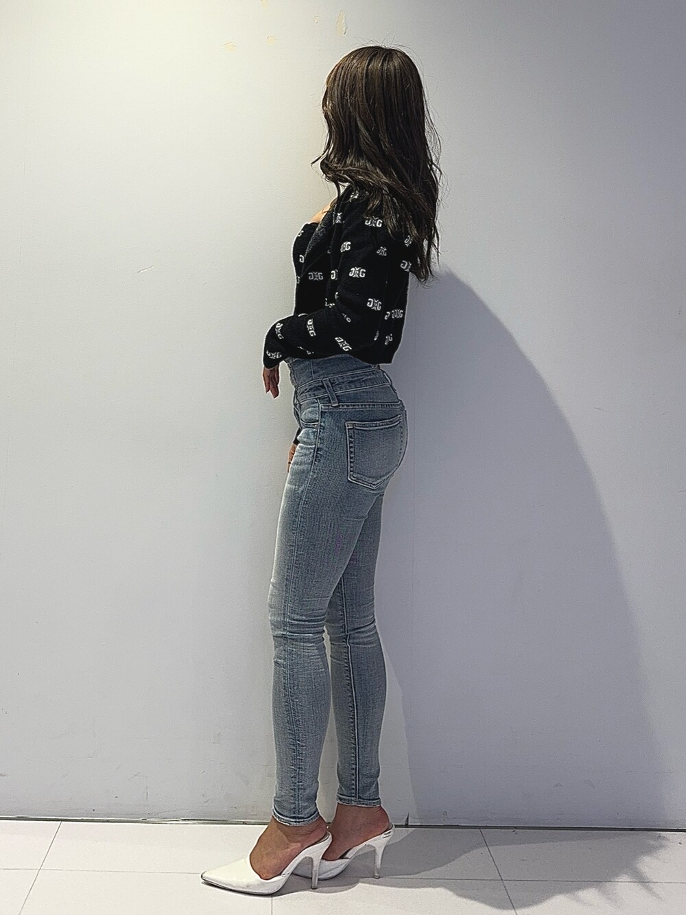 ブラック系のニット/セーター、ブルー系のデニムパンツ、ホワイト系のパンプスを着用したレディースの春コーディネートの4枚目の写真