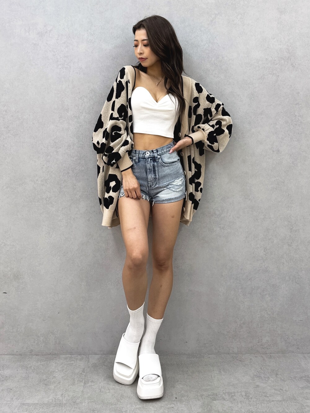 ホワイト系のチューブトップ、ベージュ系のカーディガン/ボレロ、ブルー系のデニムパンツを着用したレディースの夏コーディネートの2枚目の写真