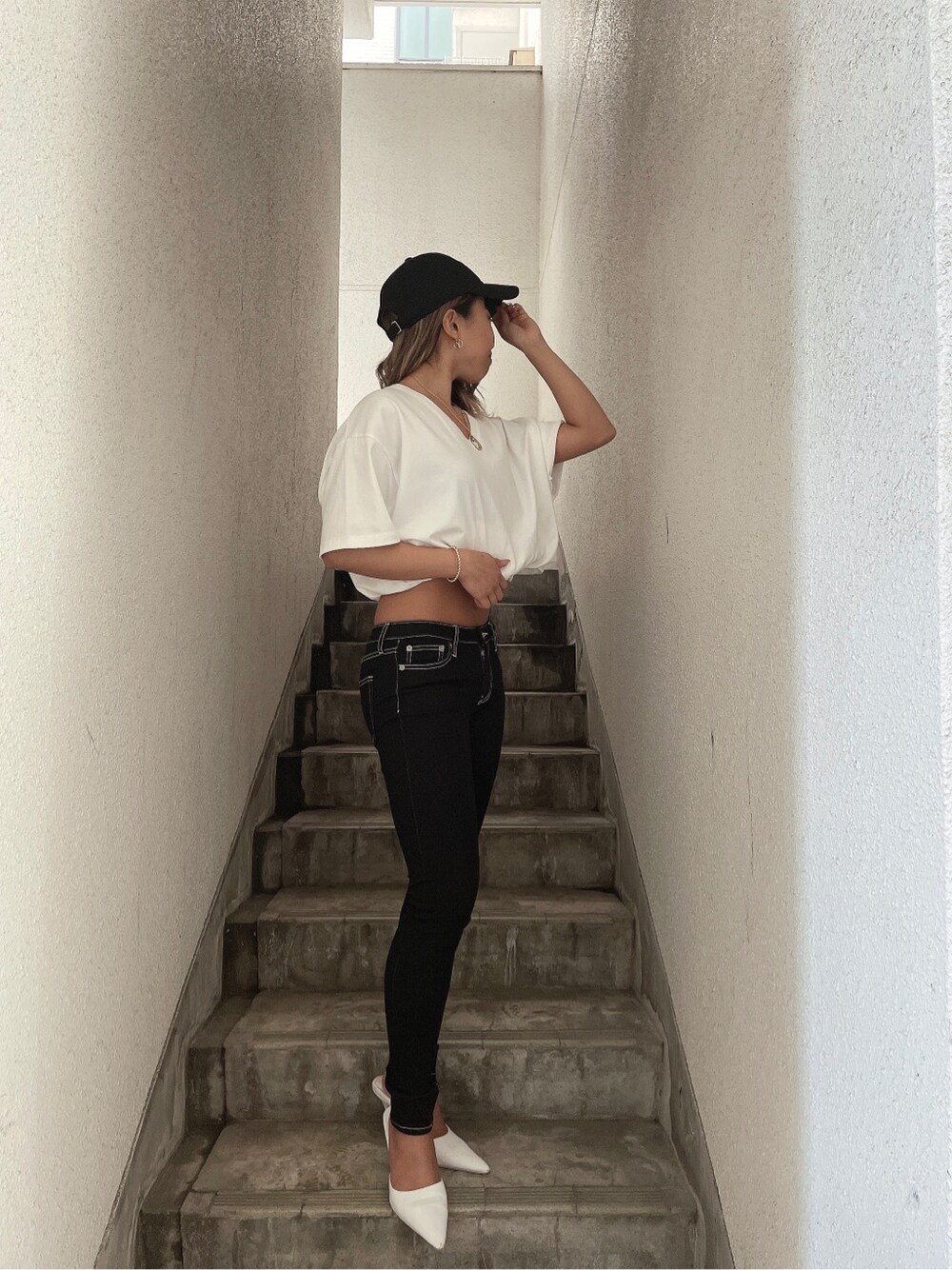 ホワイト系のTシャツ/カットソー、ホワイト系のパンプス、ブラック系のデニムパンツを着用したレディースの春コーディネートの3枚目の写真