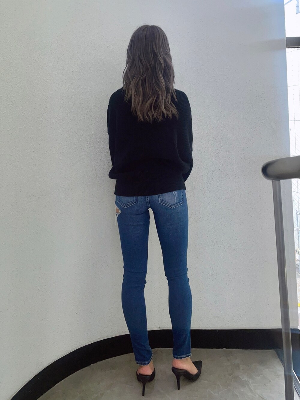 ブラック系のニット/セーター、ブルー系のデニムパンツ、ブラック系のパンプスを着用したレディースの秋コーディネートの4枚目の写真