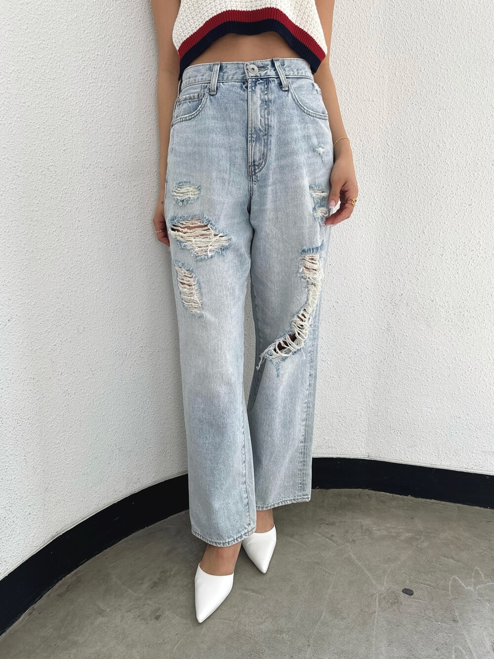 ホワイト系のニット/セーター、ブルー系のデニムパンツ、ホワイト系のパンプスを着用したレディースの春コーディネートの6枚目の写真