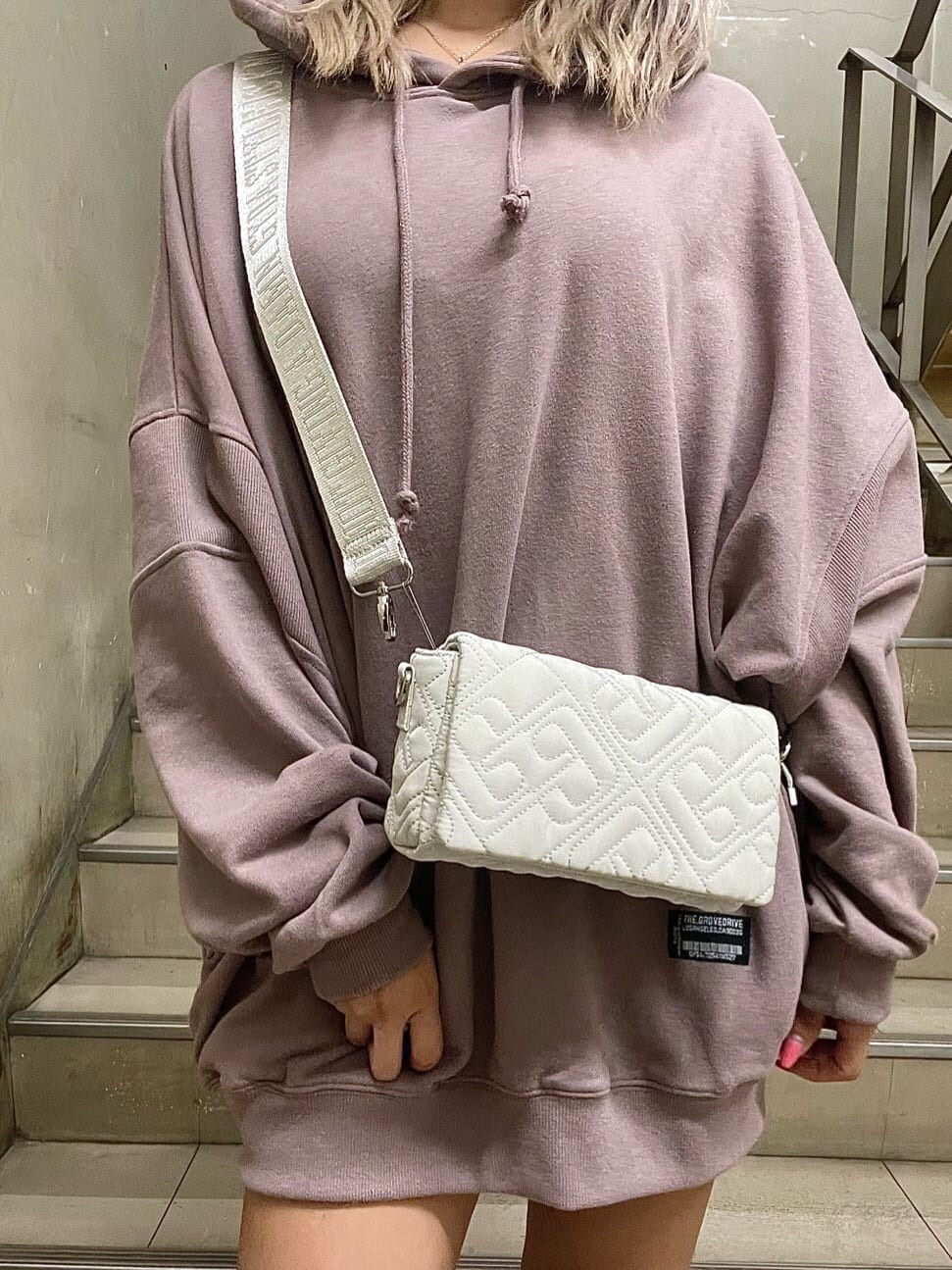 ブラック系のブーツ、ホワイト系のショルダーバッグ、ピンク系のパーカーを着用したレディースの秋コーディネートの5枚目の写真