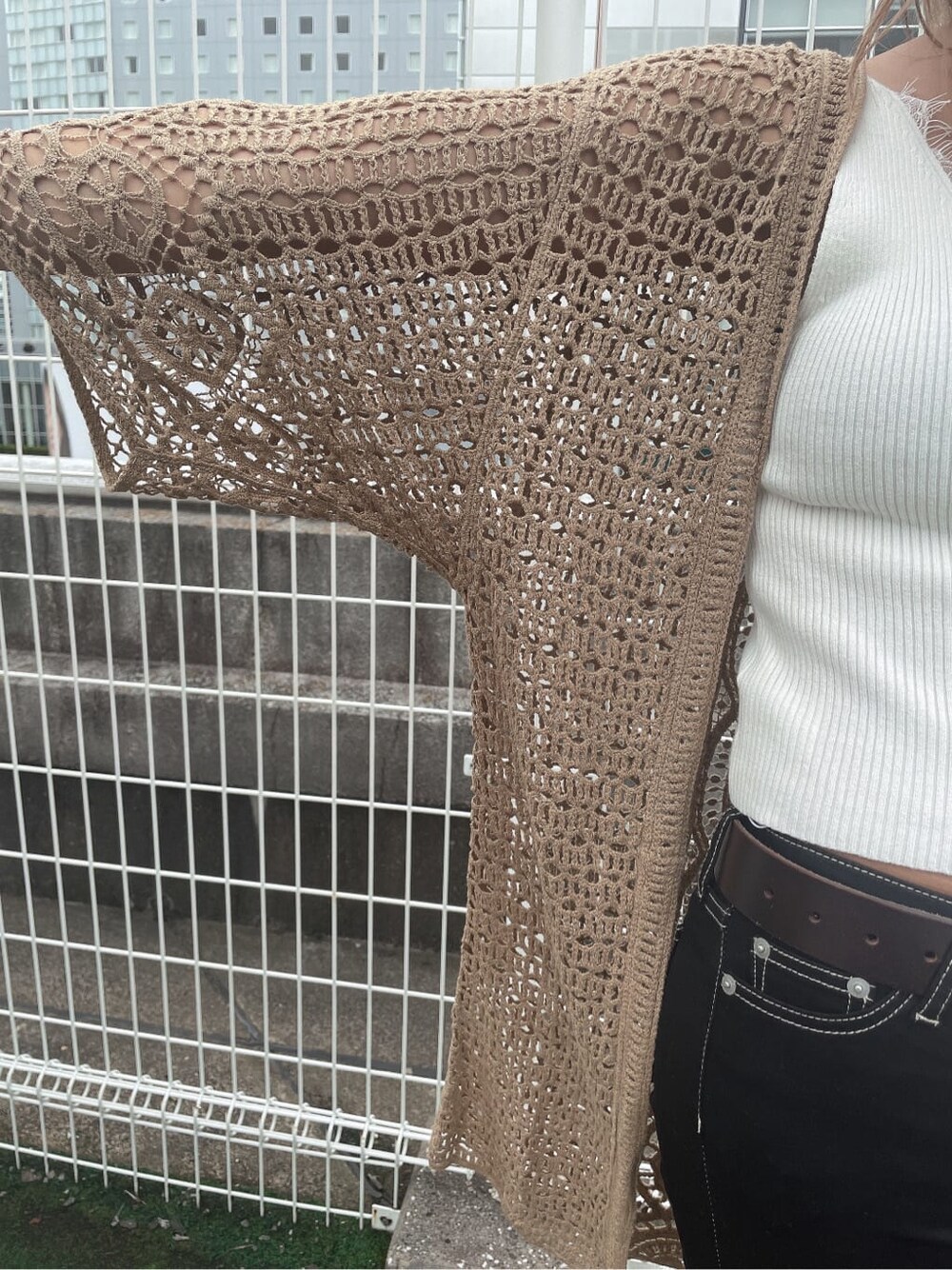 ホワイト系のニット/セーター、ブラック系のデニムパンツ、ブラック系のサンダルを着用したレディースの夏コーディネートの3枚目の写真