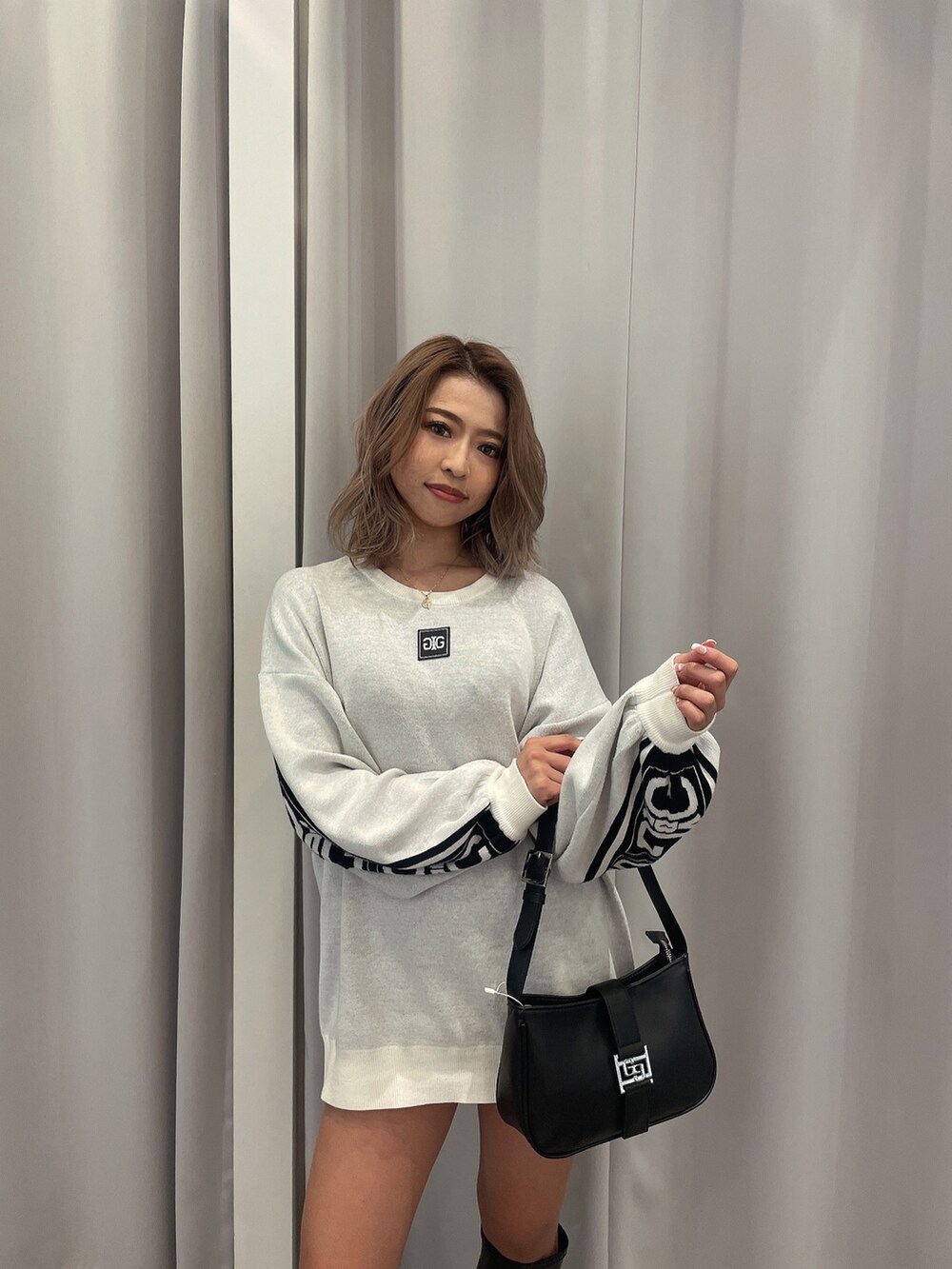 ブラック系のブーツ、ブラック系のハンドバッグ、ホワイト系のニット/セーターを着用したレディースの冬コーディネートの7枚目の写真