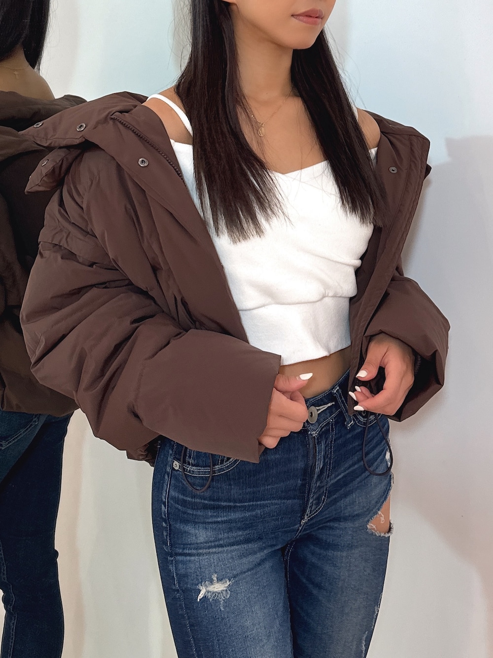 ホワイト系のTシャツ/カットソー、ブラウン系のダウンジャケット/コート、ブルー系のデニムパンツを着用したレディースの秋コーディネートの7枚目の写真